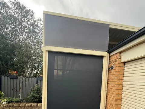 Charcoal outdoor blinds fitted to a carport-style alfresco on a cream rendered home