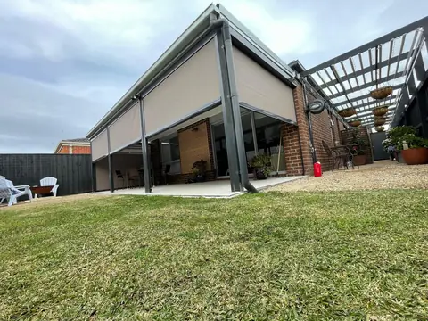 Taupe outdoor blinds enclosing a large patio and alfresco area