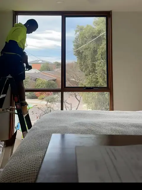 Shelton on a ladder fitting a timber venetian blind to a bedroom window